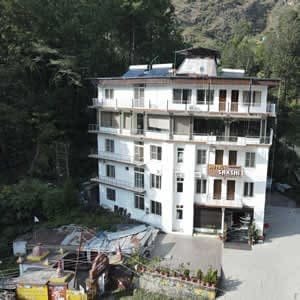 Exterior building view of Hotel Sakshi Uttarkashi, a multi-story hotel in Uttarkashi surrounded by greenery