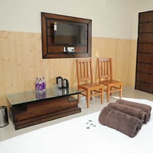 Room interior with flat-screen TV and wooden paneling at Hotel Sakshi Uttarkashi, the best hotel in Uttarkashi for families
