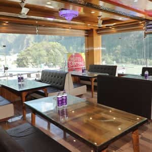 In-house restaurant at Hotel Sakshi with large windows offering a beautiful Uttarkashi hotel experience.