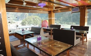 Bright dining area at Hotel Sakshi, a premier Sakshi hotel in Uttarkashi offering beautiful views through large glass windows.